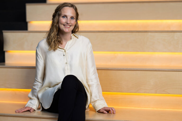 Anita Oien, medarbejder i AKKC, sidder p&aring; en trappe og smiler